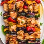 Grilled chicken kabobs with vegetables on a white platter