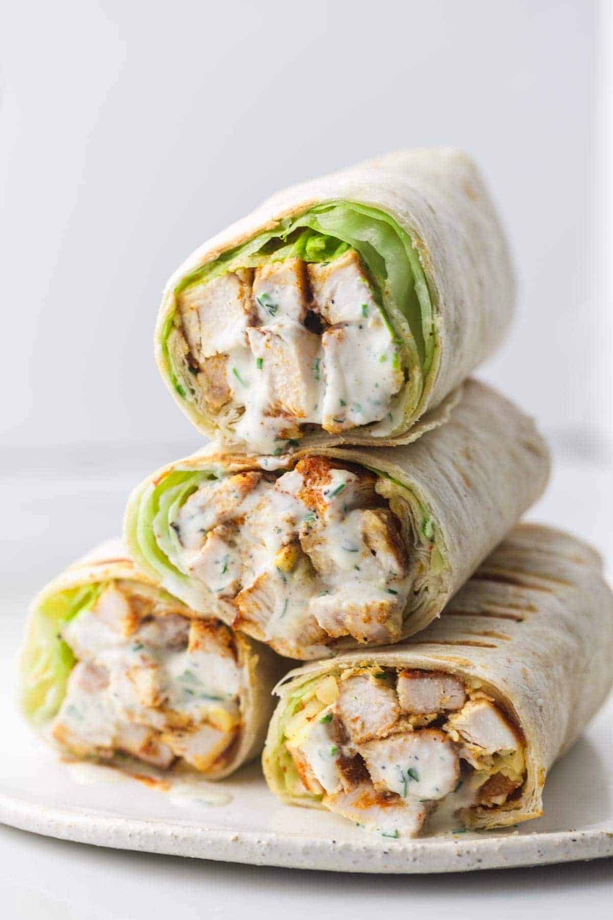 4 grilled chicken wraps stacked on a plate