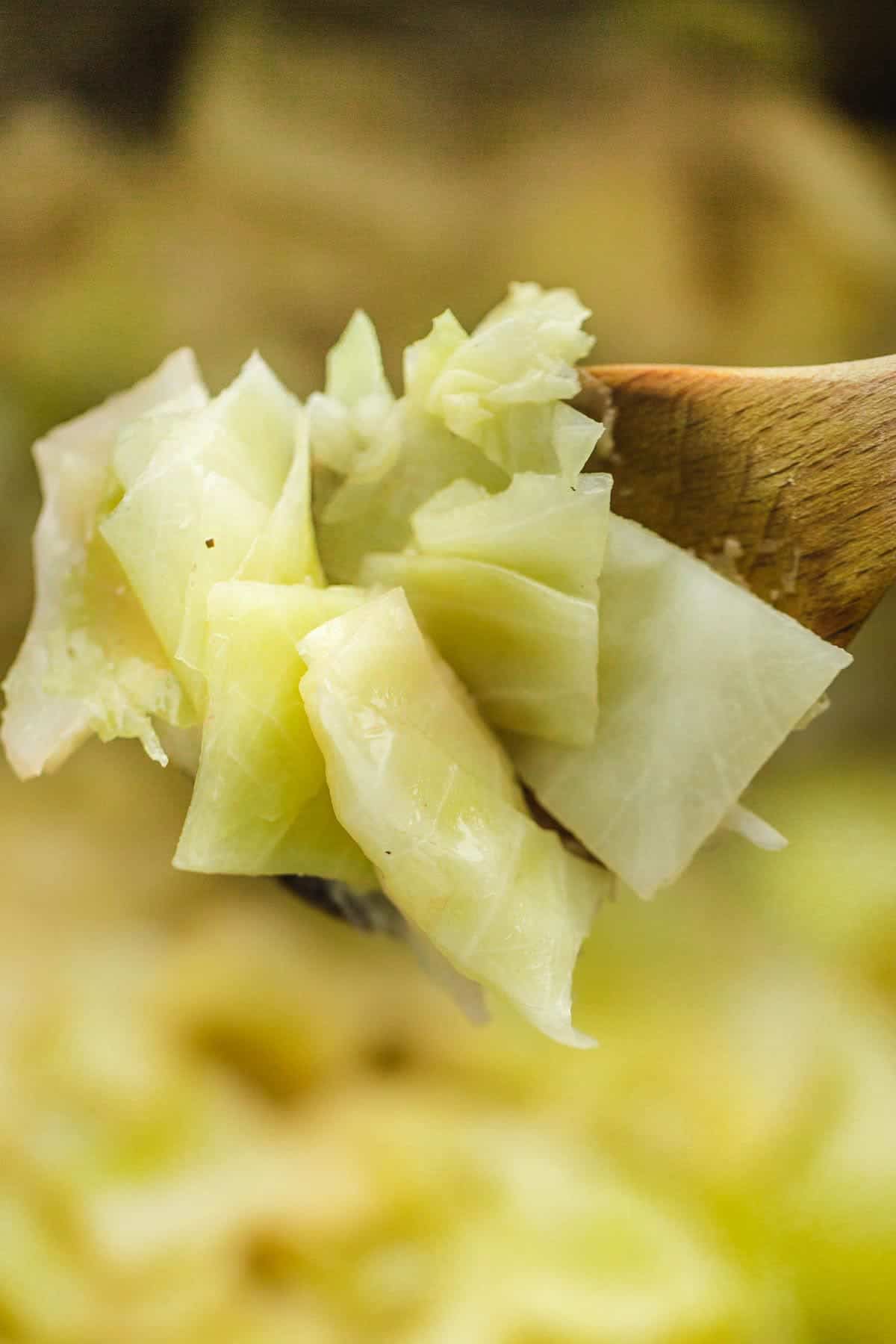 A close up of buttered cabbage on a wooden spoon
