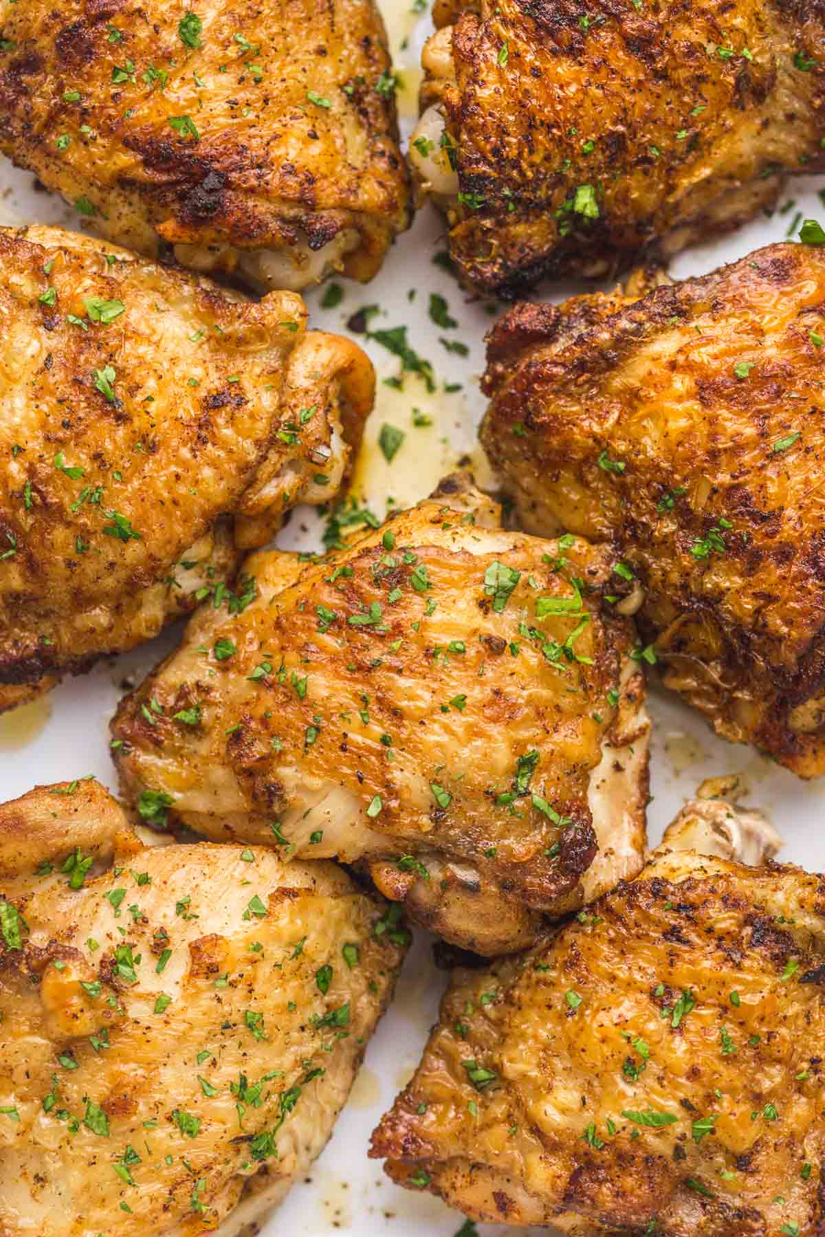 Close up shot of browned chicken thighs, garnished with chopped parsley