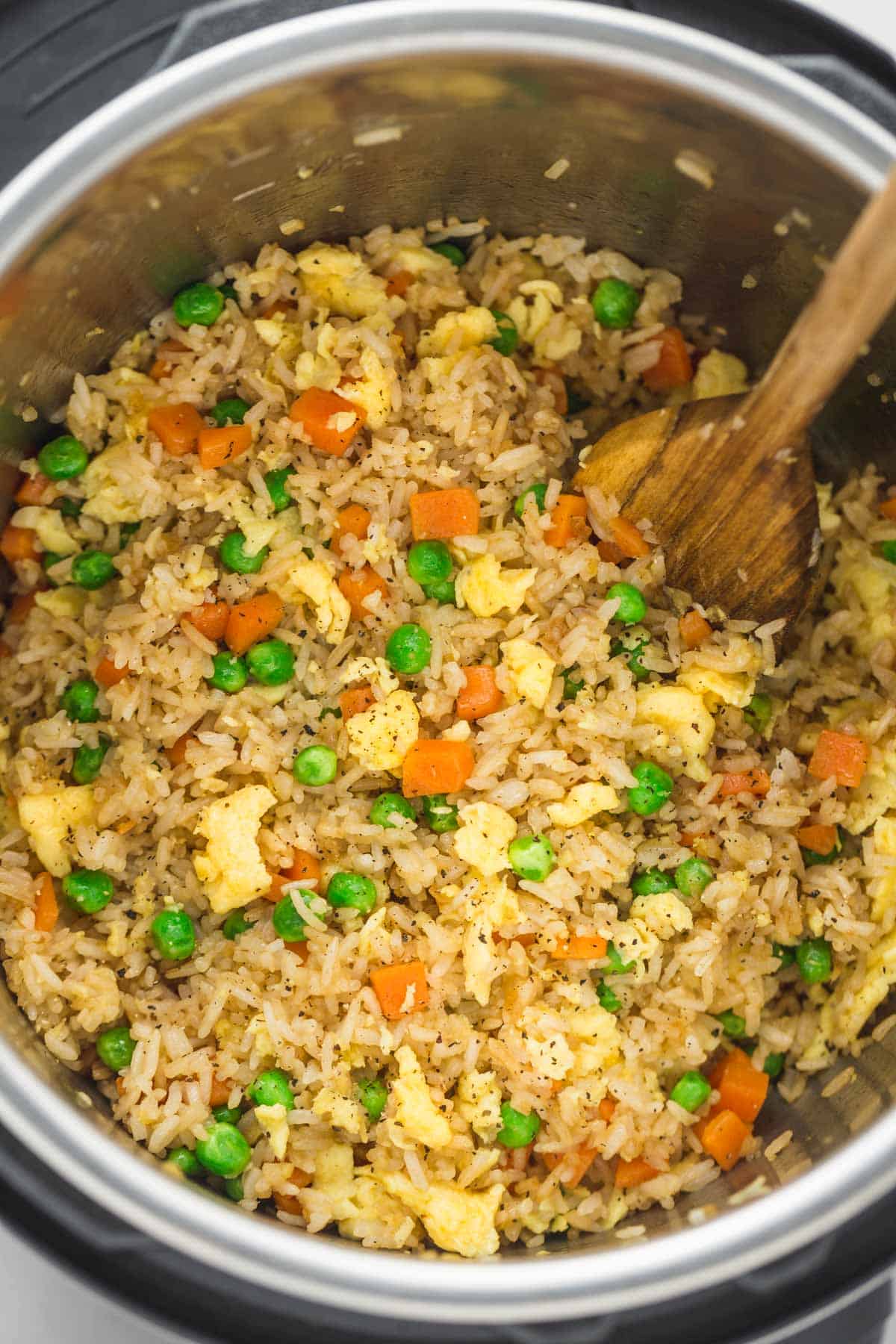 Fried rice in the instant pot with a wooden spoon