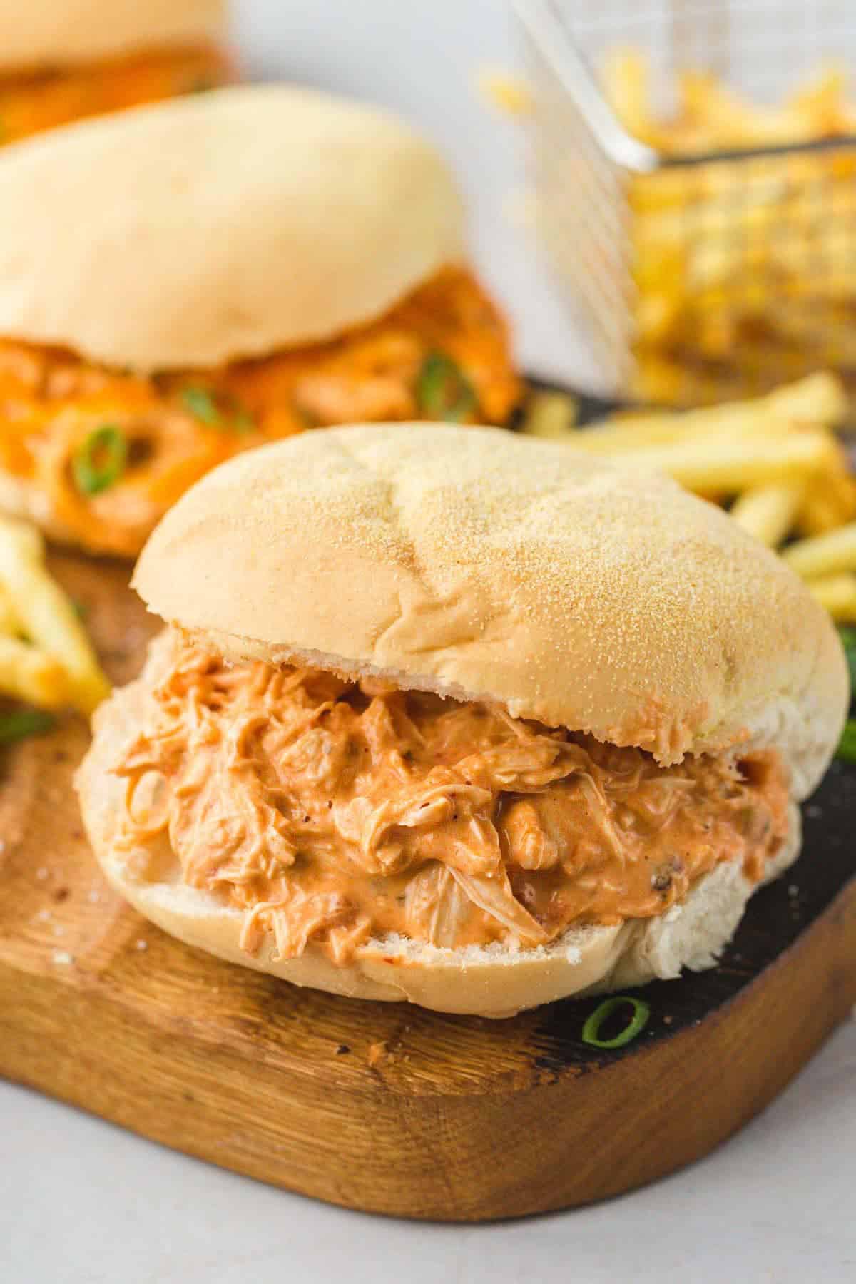 Creamy salsa shredded chicken sliders with French fries on a wooden board