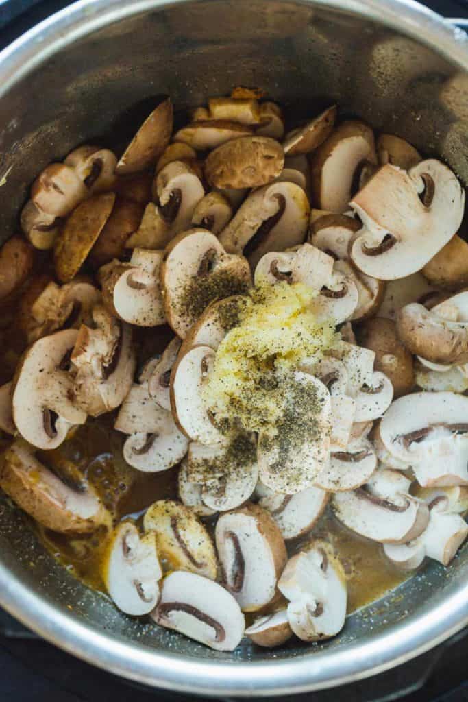 Adding mushrooms, garlic, salt, and pepper to the Instant Pot