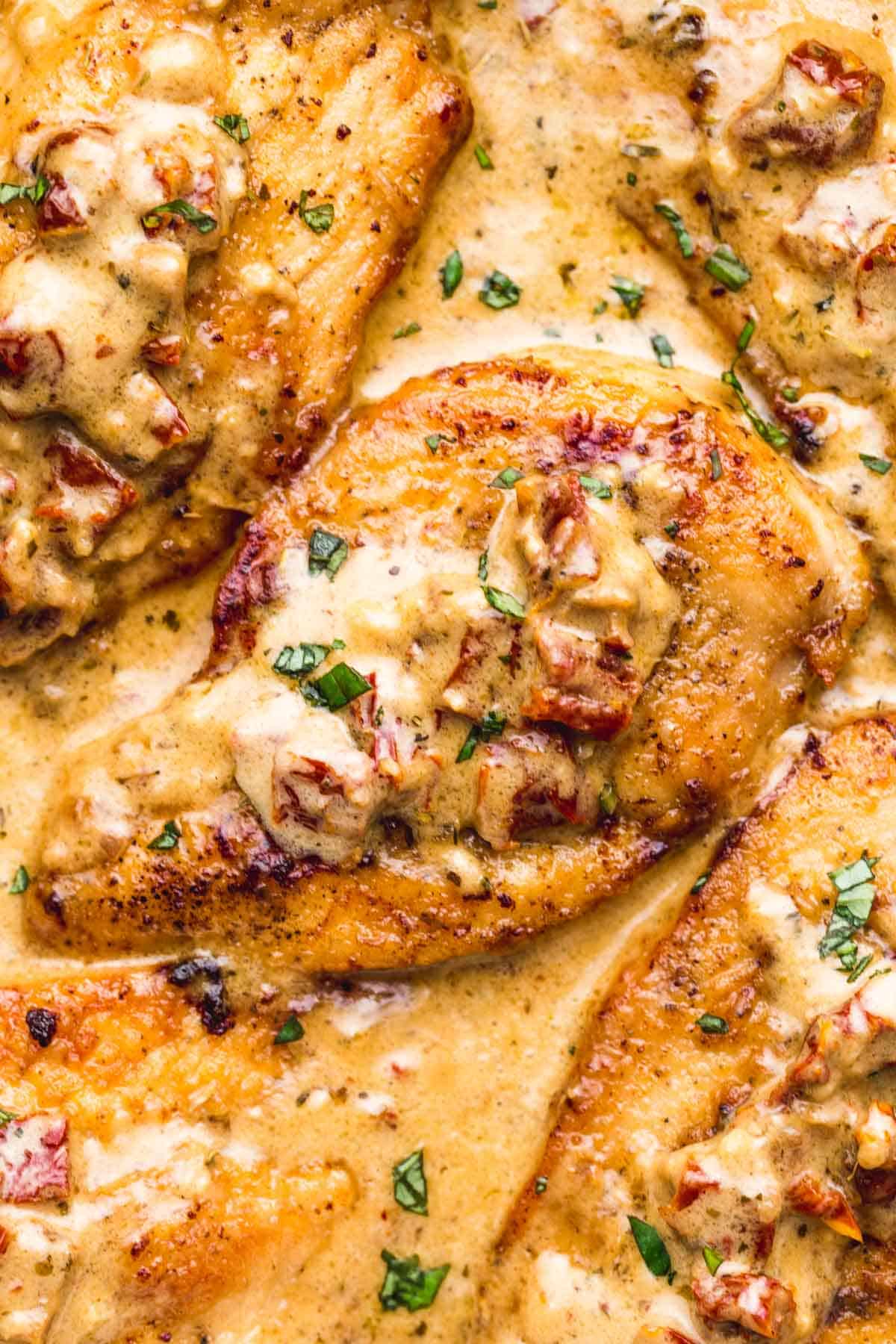 A close up shot of marry me chicken cutlets smothered in creamy sauce and sundried tomatoes