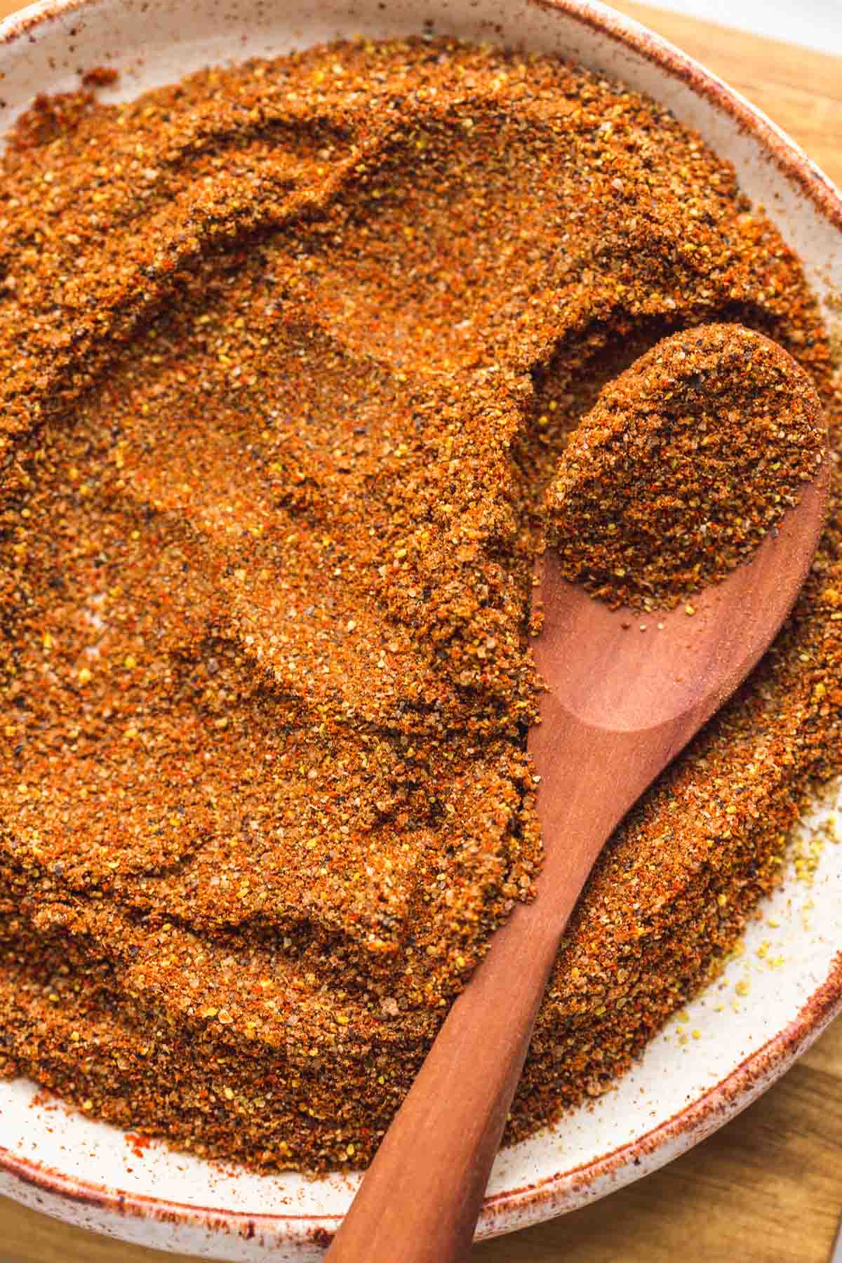 A close up of Old bay seasoning on a small plate with a wooden spoon