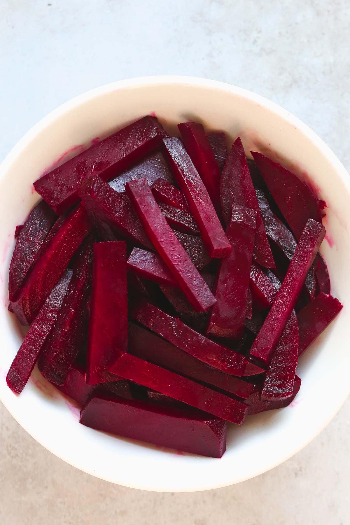 Sliced match stick beets in a white bowl