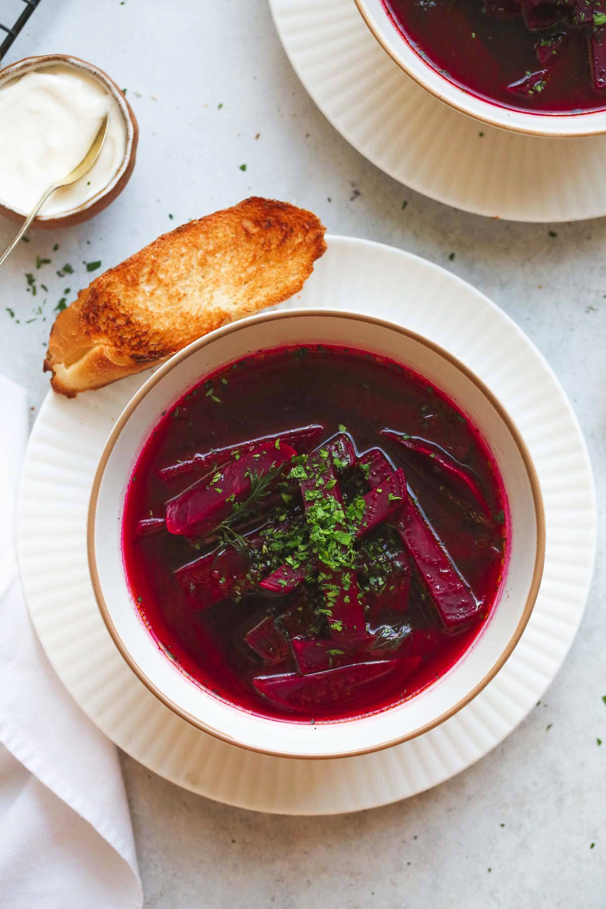 a bowl of Polish beet soup in a white bowl with a piece of toasted bread