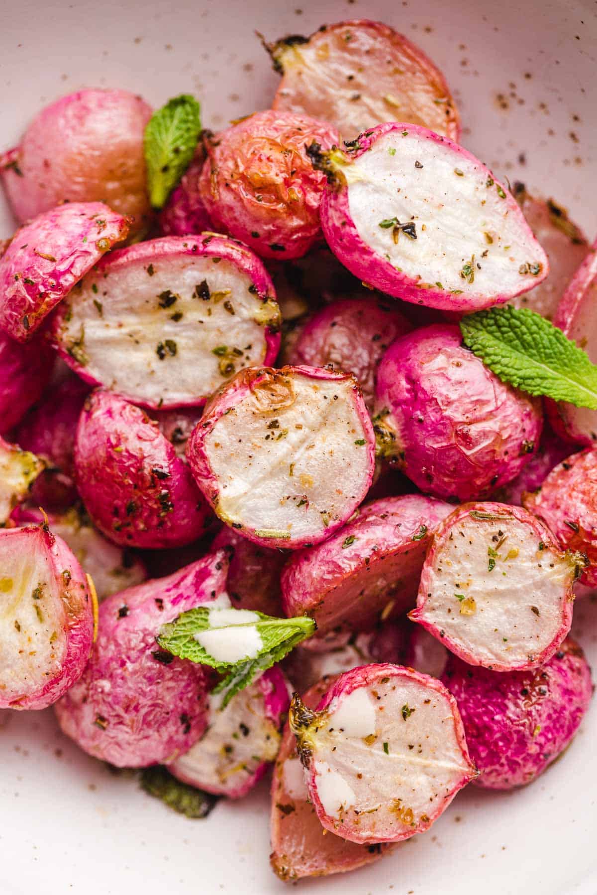 Roasted radishes in a bowl with fresh mint leaves