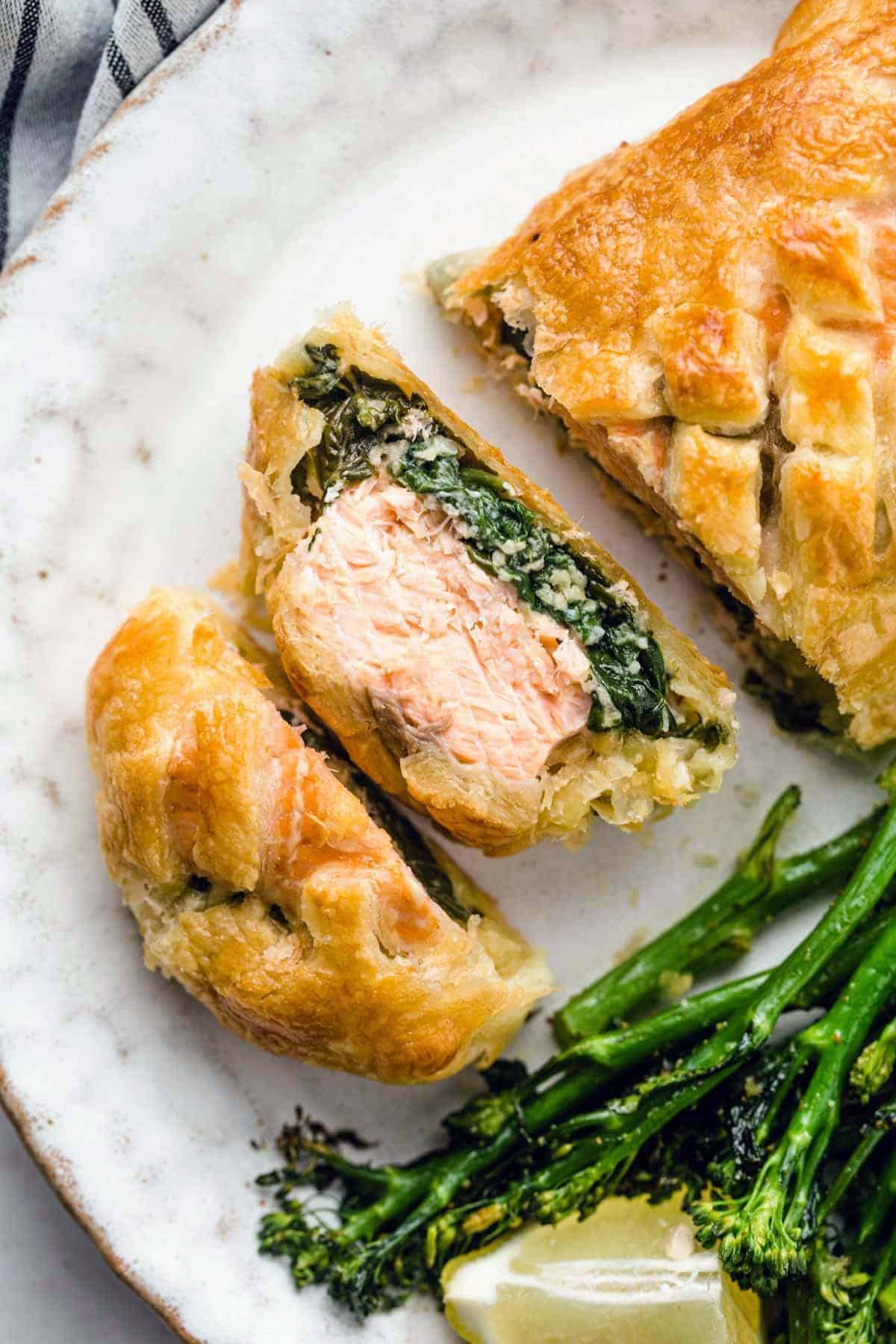 Salmon Wellington on a plate, served with steamed broccolini and a lemon wedge