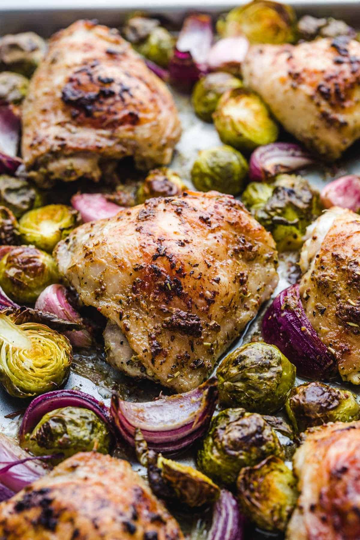 Sheet pan chicken thighs with brussels sprouts, red onion, and garlic.