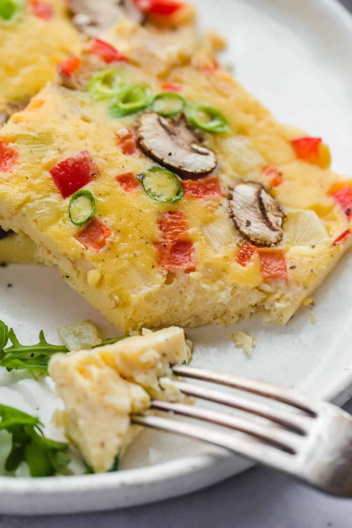 Taking a bite of the sheet pan eggs using a fork to show the right texture