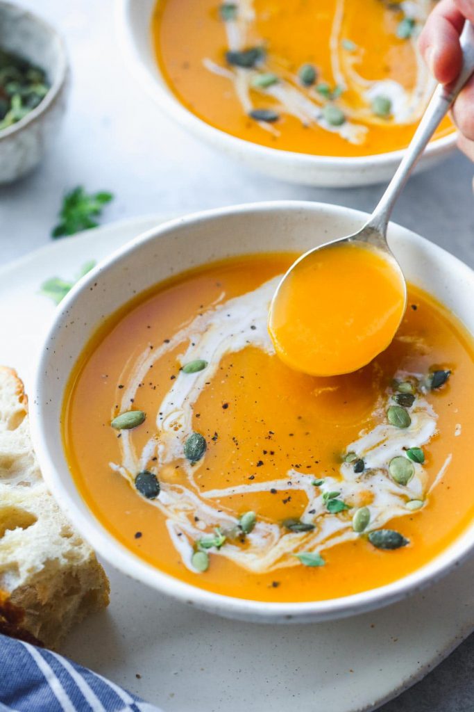 A bowl of Slow Cooker Butternut Squash and Sweet Potato Soup and a spoonful