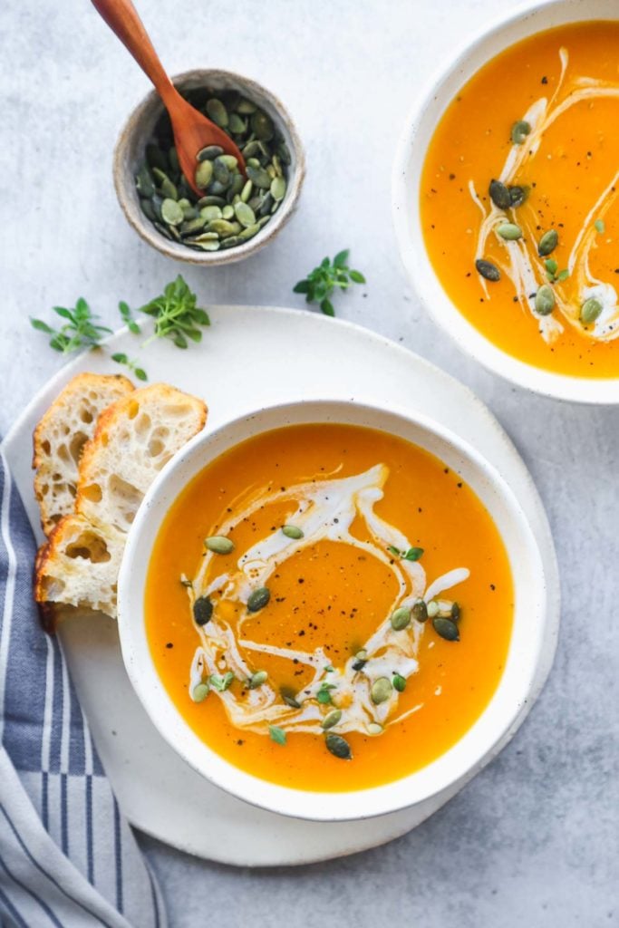 A bowl of Slow Cooker Butternut Squash Soup with a piece of focaccia 