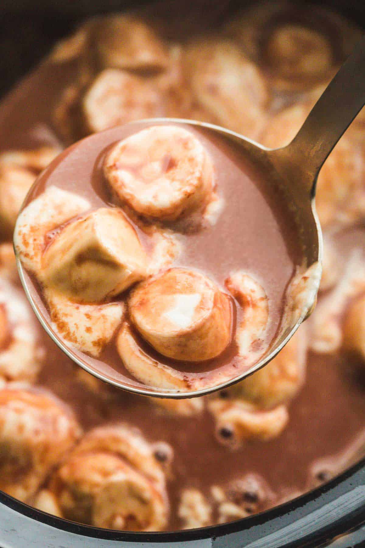 A stainless steel ladle with hot chocolate and melted marshmallows