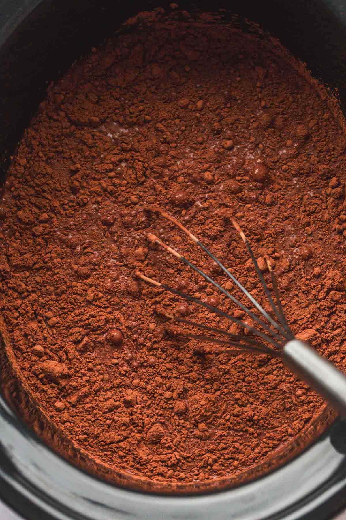 Whisking the milk with cocoa powder, sugar, vanilla, and chocolate chips