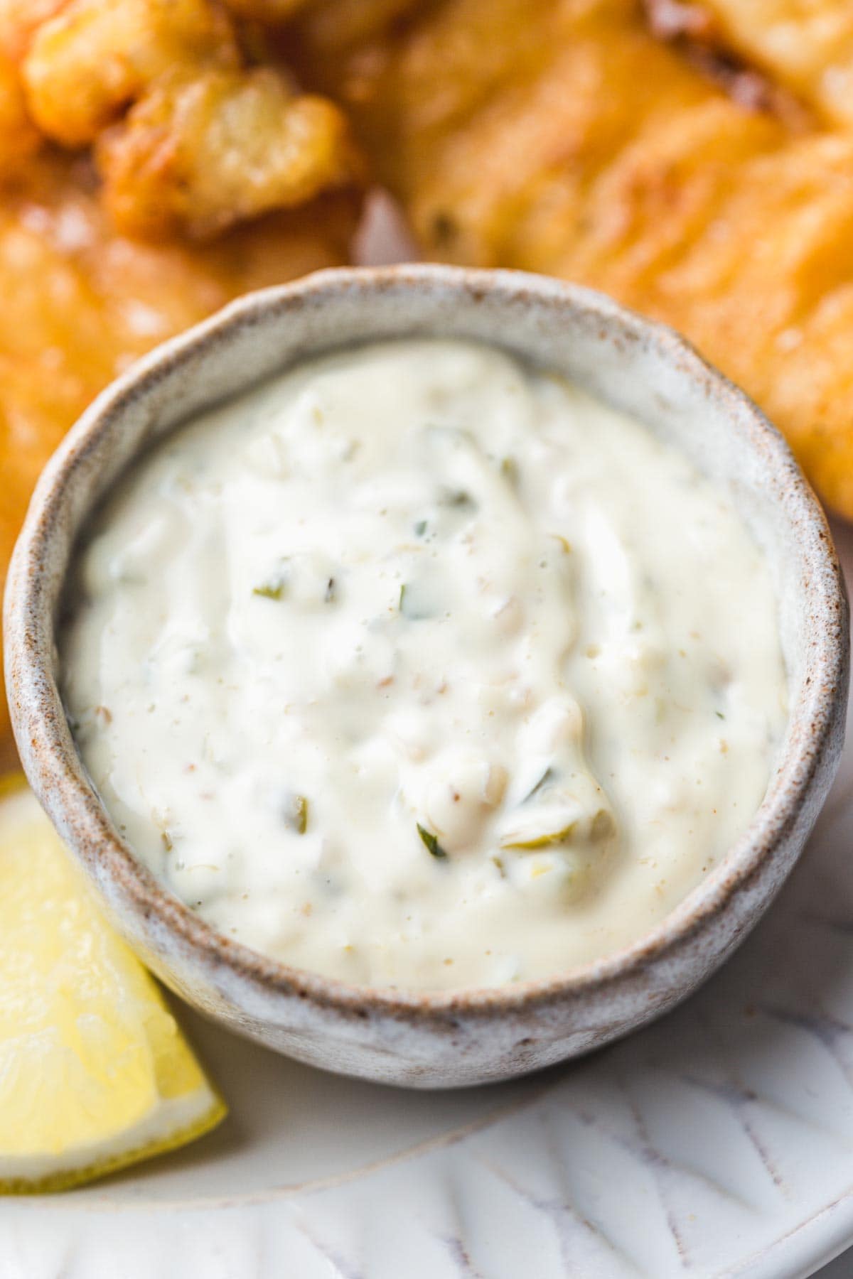 Tartar sauce in a small ceramic pinch bowl, and a lemon wedge on the side