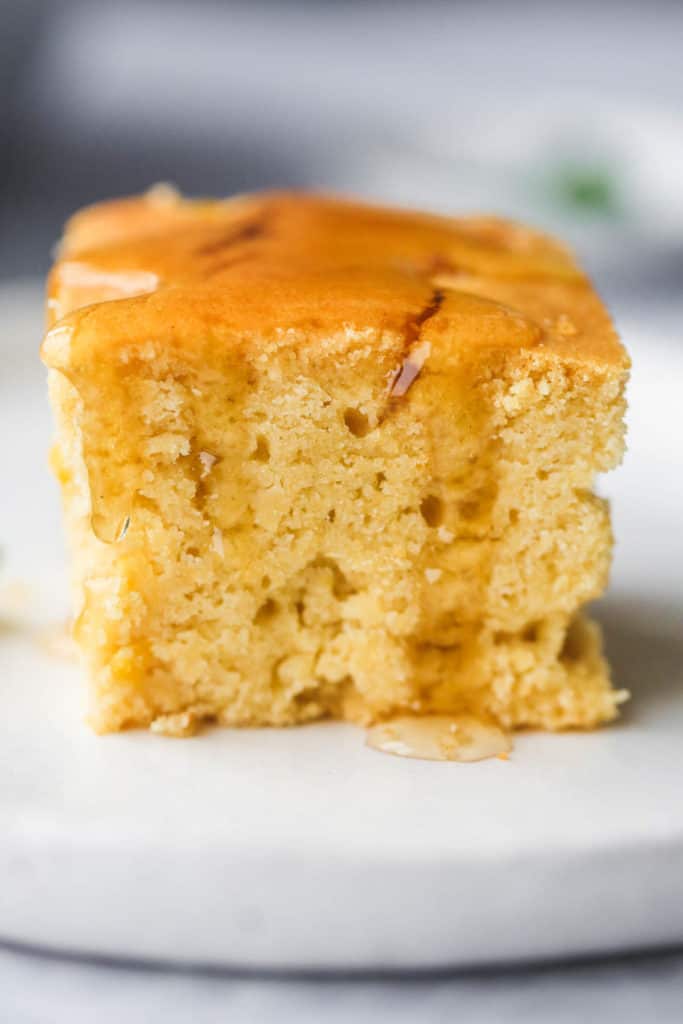 A close up shot of cornbread with honey or agave or maple.