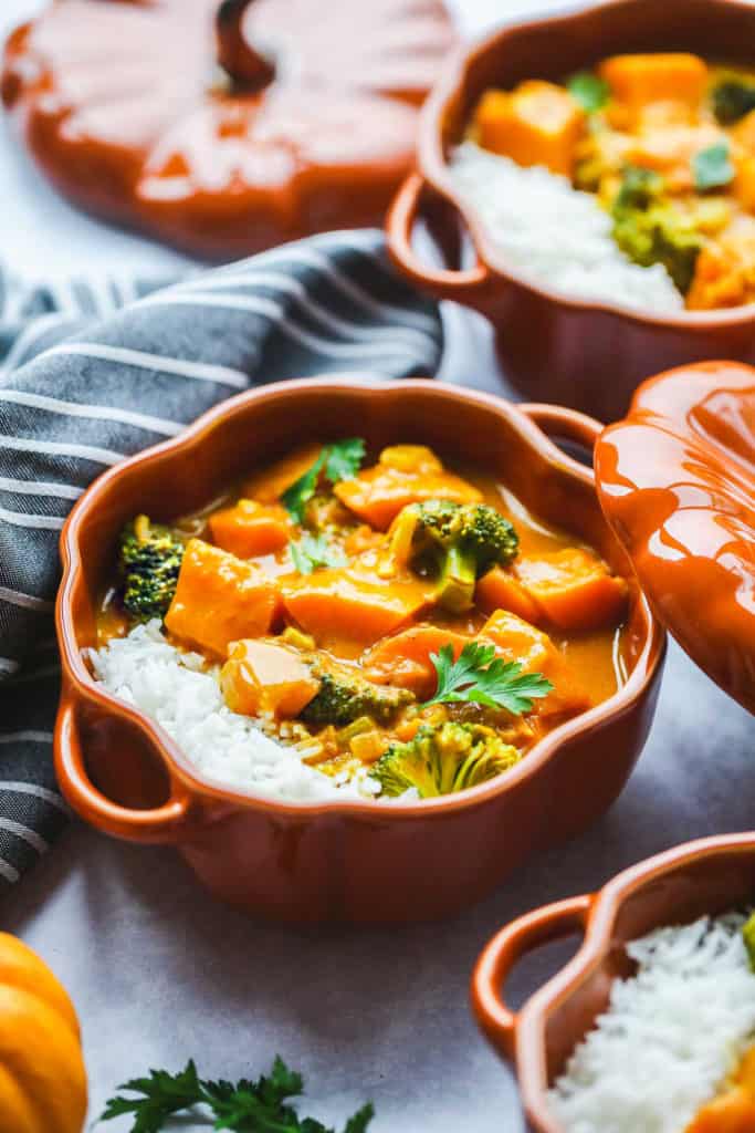 Pumpkin curry with broccoli served over white rice in a small Staub pumpkin cocotte