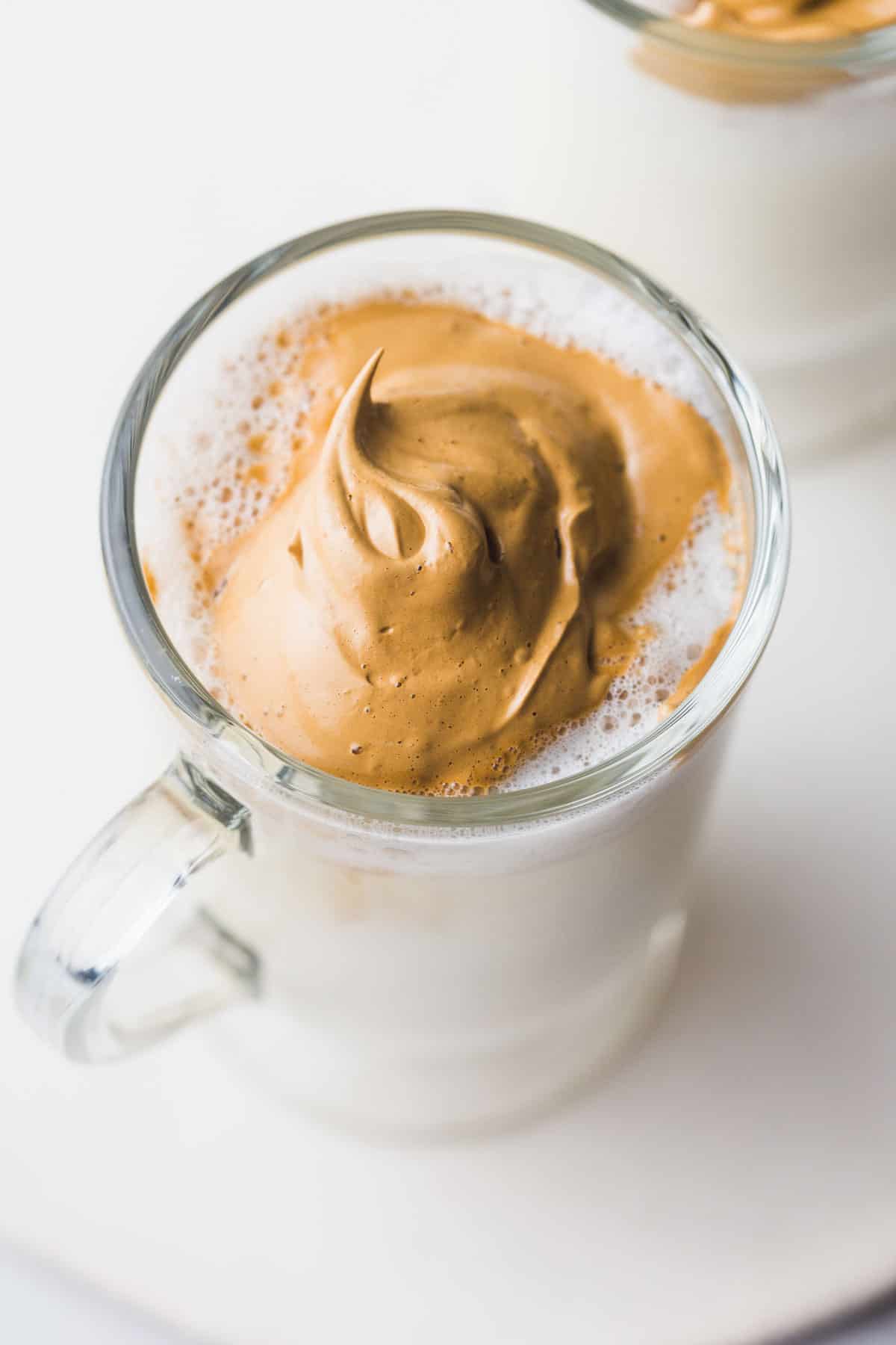 Whipped cream in a glass mug with warm vegan milk