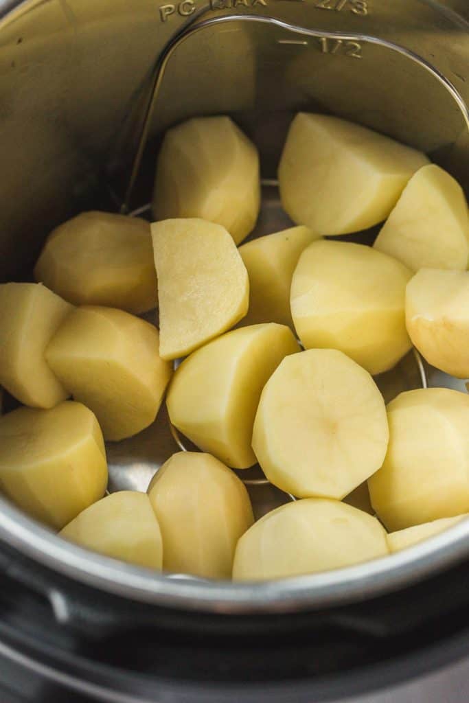 Raw peeled and chopped potatoes in an Instant Pot sitting over a trivet